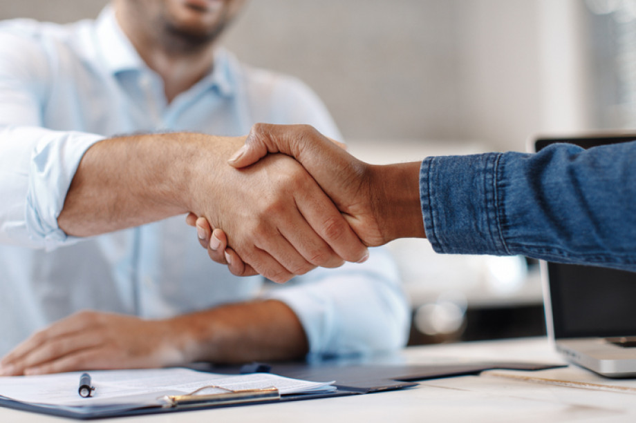 Two people shaking hands over a desk