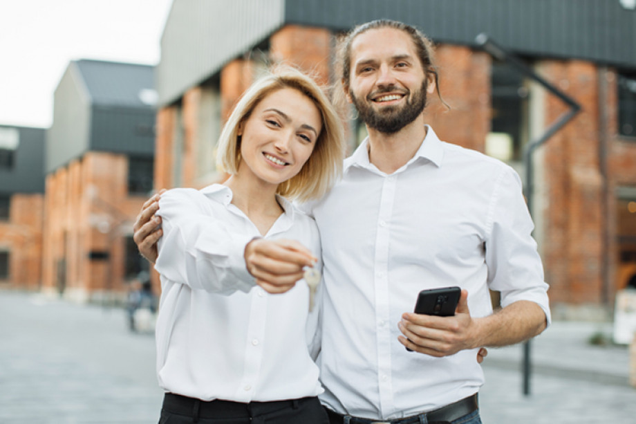 Photo of two people in white shirts holding the keys to their new home