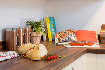 Photo of a kitchen counter with bread, tomatoes and an open recipe book