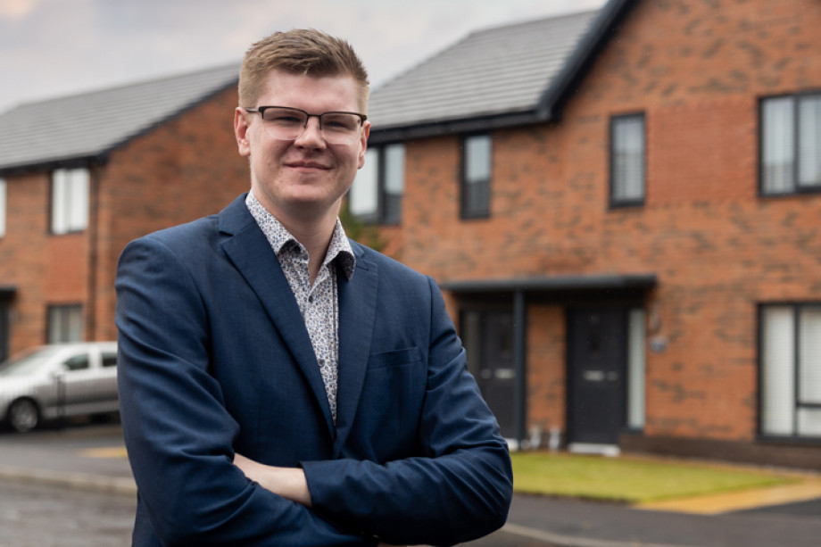 Photo of someone with their arms folded stood in front of a row of houses