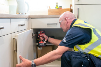 Photo of a HMS operative fitting a kitchen cabinet door