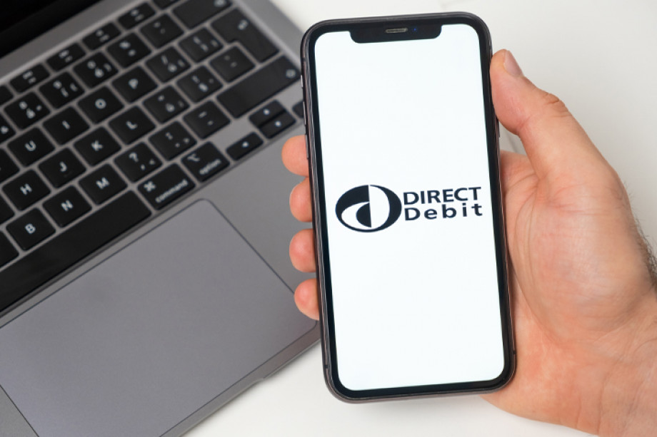 Photo of someone holding a mobile phone which has the Direct Debit logo open on it