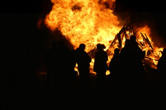 Photo of people stood in front of a bonfire